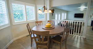 Dining area with hardwood / wood-style floors, suspended lighting, and a fireplace