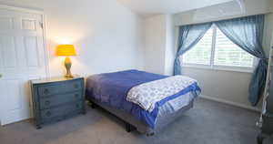 Bedroom featuring dark colored carpet and baseboards