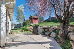 Fenced backyard with a patio area, a grill, and a storage shed