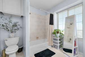 Bathroom with shower / bath combo with shower curtain and light flooring