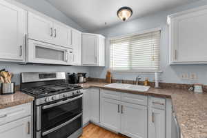Kitchen with double oven range, white microwave, and white cabinets