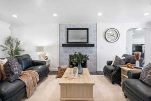 Living room featuring arched walkways, light wood-style floors, a tile fireplace, recessed lighting, and crown molding
