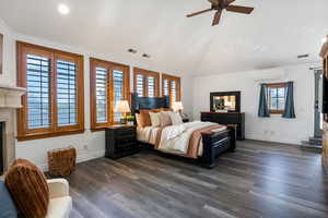 Bedroom with vaulted ceiling, dark wood-style flooring, a fireplace, a ceiling fan, and recessed lighting