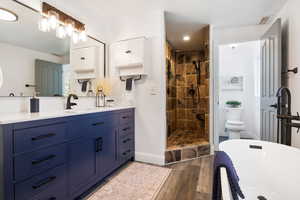 Full bathroom with vanity, a shower stall, dark wood-style floors, a soaking tub, and recessed lighting
