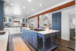 Kitchen with dark wood-style floors, two tone cabinets, decorative backsplash, a center island, and a breakfast bar area