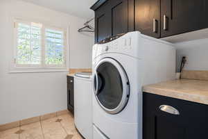 Laundry room with cabinet space and light tile patterned floors