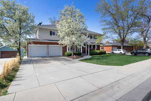 View of front facade featuring driveway, a garage, a front lawn, brick siding, and roof with shingles