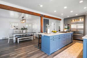 Kitchen featuring stainless steel appliances, blue cabinetry, dark wood-type flooring, a breakfast bar, and ornamental molding