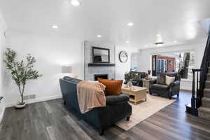 Living area featuring dark wood finished floors, ornamental molding, recessed lighting, and a fireplace