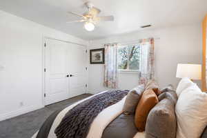 Carpeted bedroom featuring a ceiling fan and a closet