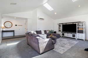Carpeted living room featuring a skylight, vaulted ceiling, and recessed lighting