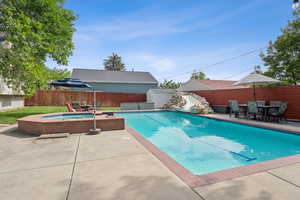 View of swimming pool with outdoor dining area, patio surround, a storage unit, and a fenced backyard