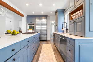 Kitchen featuring light wood-style flooring, blue cabinetry, stainless steel appliances, recessed lighting, and light stone countertops