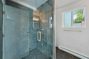 Full bathroom featuring a baseboard radiator and a stall shower