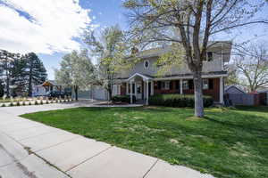 View of front of home with a front lawn, brick siding, concrete driveway, and a chimney