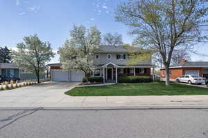 Traditional home featuring a front lawn, driveway, and a garage