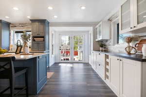 Kitchen featuring backsplash, recessed lighting, glass fronted cabinets, dark wood finished floors, and french doors