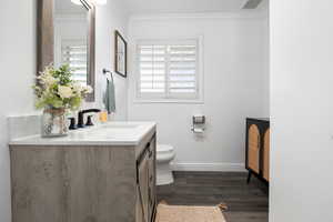 Bathroom featuring vanity, dark wood-type flooring, and ornamental molding