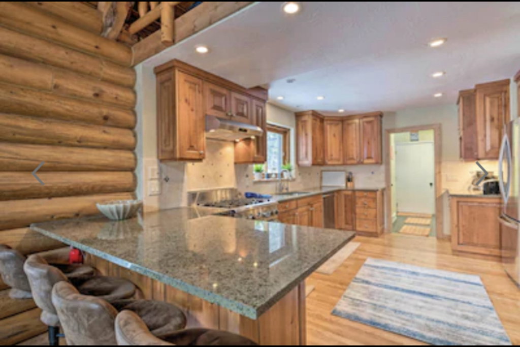 Kitchen featuring wood finish cabinets, light stone counters, a peninsula, stainless steel appliances, and a breakfast bar area