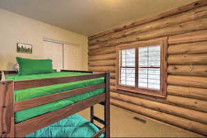Bedroom with log walls, a closet, and carpet flooring