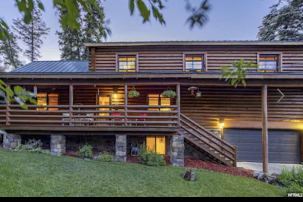 View of front of property with a garage, a front yard, a porch, and a metal roof