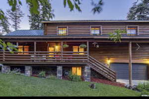 View of front of property with a garage, a front yard, a porch, and a metal roof