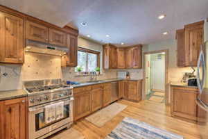 Kitchen with wood finish cabinetry, stainless steel appliances, light wood finished floors, and recessed lighting