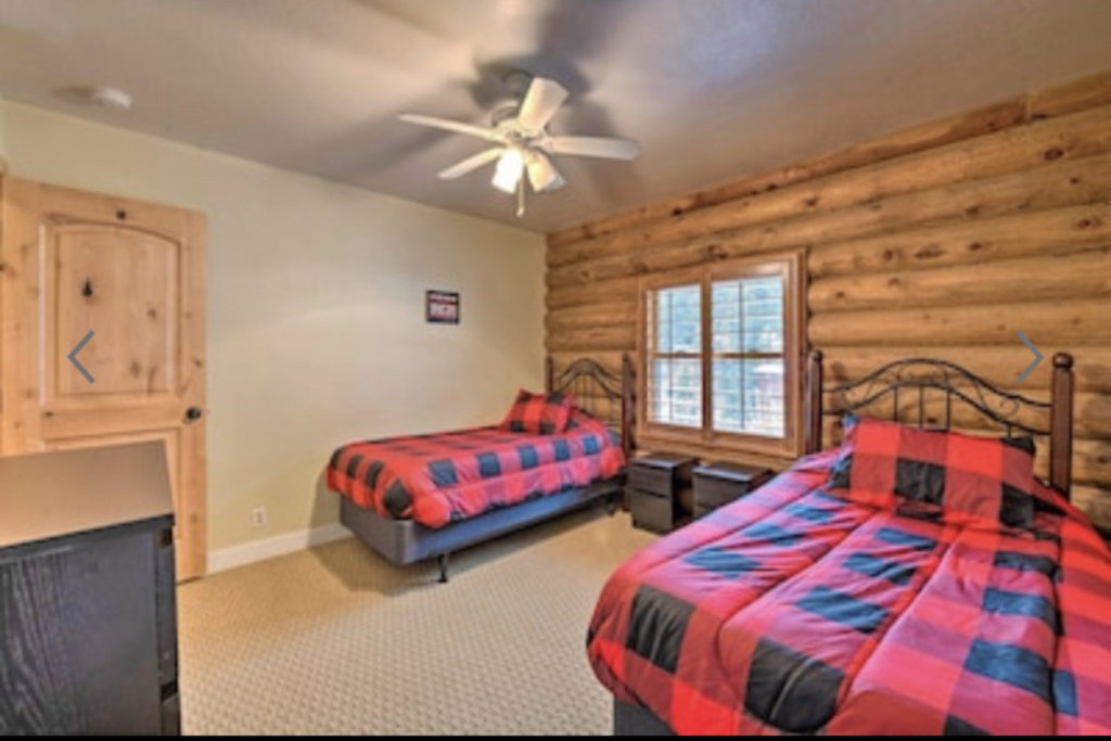 Bedroom with rustic walls, light colored carpet, and ceiling fan