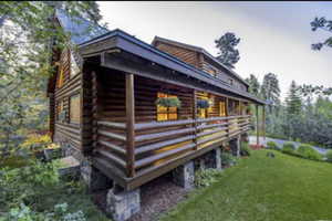 View of side of home with log exterior and a yard