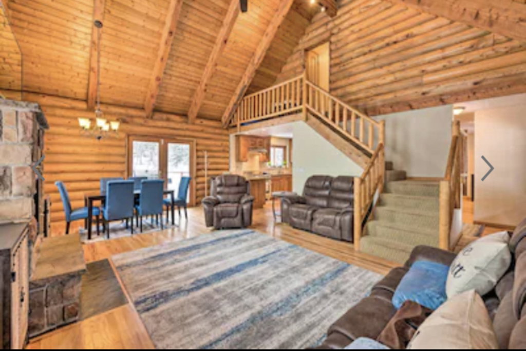Living room with a high wooden beamed ceiling, hardwood / wood-style flooring, rustic walls, and suspended lighting