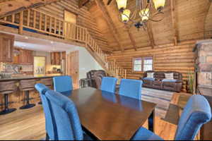 Dining room featuring log walls, a high wooden beamed ceiling, wood finished floors, and a chandelier