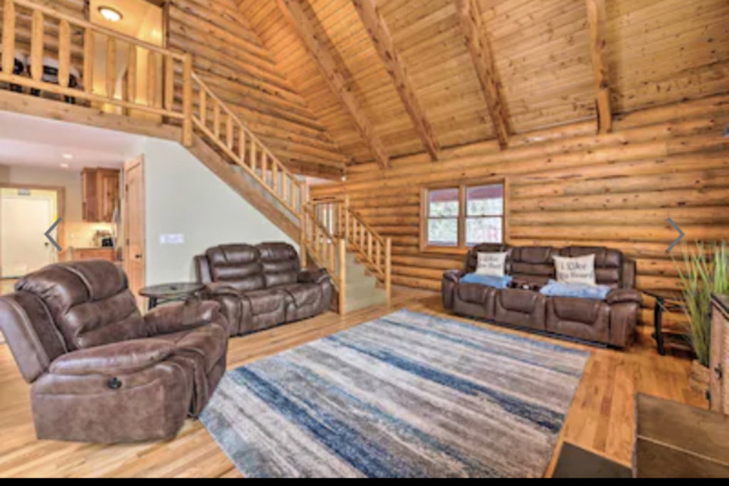Living room with a high wooden beamed ceiling, hardwood / wood-style floors, and rustic walls