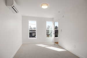 Spare room featuring a wall mounted mini split and light colored carpet