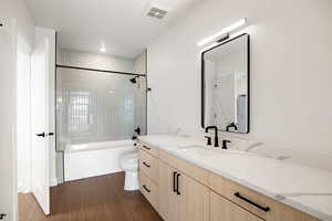 Bathroom featuring vanity, bathing tub / shower combination, and dark wood-style flooring