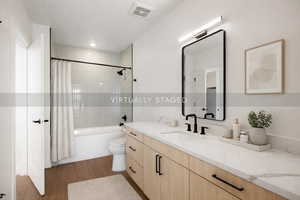 Full bath with vanity, shower / tub combo with curtain, and dark wood-style floors