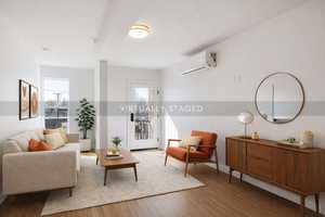 Living room featuring light wood finished floors, a wall mounted mini split, and a textured ceiling