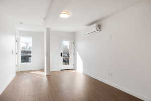 Unfurnished room with light wood finished floors and a wall mounted mini split
