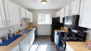 Kitchen featuring black appliances, white cabinets, light countertops, and dark wood-type flooring