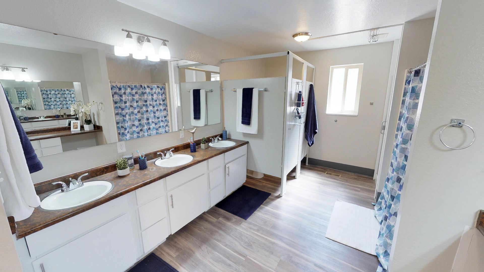Full bathroom featuring double vanity, light wood-type flooring, and a shower with curtain
