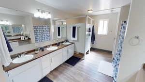 Full bathroom featuring double vanity, light wood-type flooring, and a shower with curtain