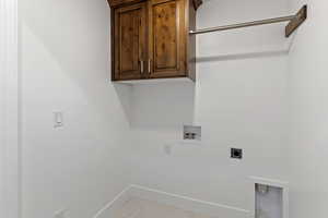 Laundry area with electric dryer hookup, cabinet space, washer hookup, and light marble finish flooring