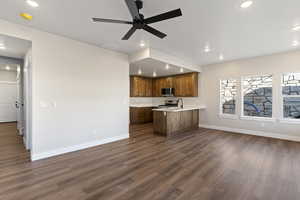 Kitchen featuring a peninsula, light countertops, wood finish cabinets, ceiling fan, and dark wood-type flooring