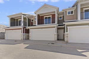 View of front of property with stone siding, a balcony, and an attached garage