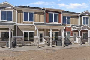 View of front of house featuring board and batten siding, stone siding, and a shingled roof