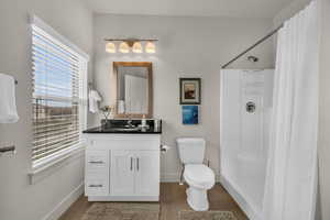Full bath featuring a stall shower, vanity, and dark wood-style floors