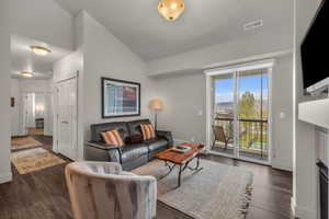 Living area with lofted ceiling and dark wood-style flooring