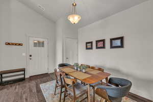 Dining area with dark wood finished floors and lofted ceiling