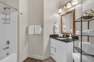 Bathroom with vanity, shower / tub combination, and dark wood-style flooring