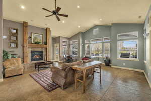 Living room featuring a high ceiling, a ceiling fan, a glass covered fireplace, and recessed lighting