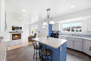 Kitchen featuring a kitchen island, a breakfast bar, open floor plan, white cabinets, and a tile fireplace